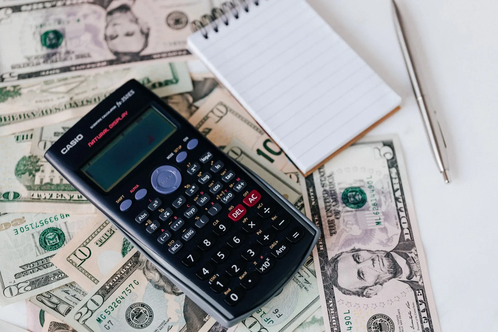 Calcul de costuri pentru un sistem fotovoltaic, cu cifre notate pe hârtie și calculator alături