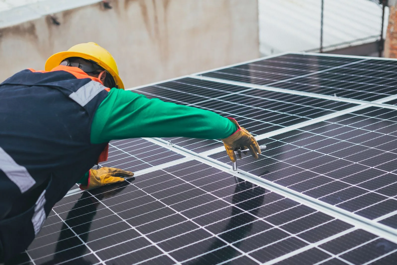 Montaj panouri fotovoltaice pe acoperiș: tehnician fixând clemele de prindere