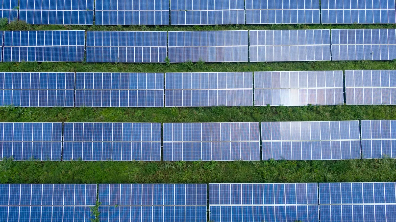 Vedere aeriană a unui parc fotovoltaic la sol cu rânduri de module pe structuri metalice