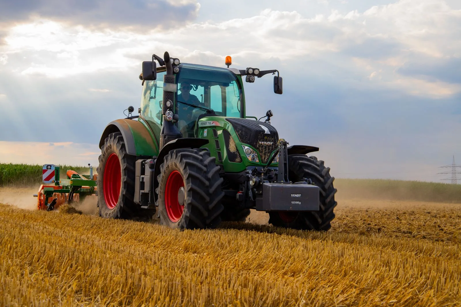 Tractor cu utilaj agricol lucrând pe un teren cu resturi de recoltă